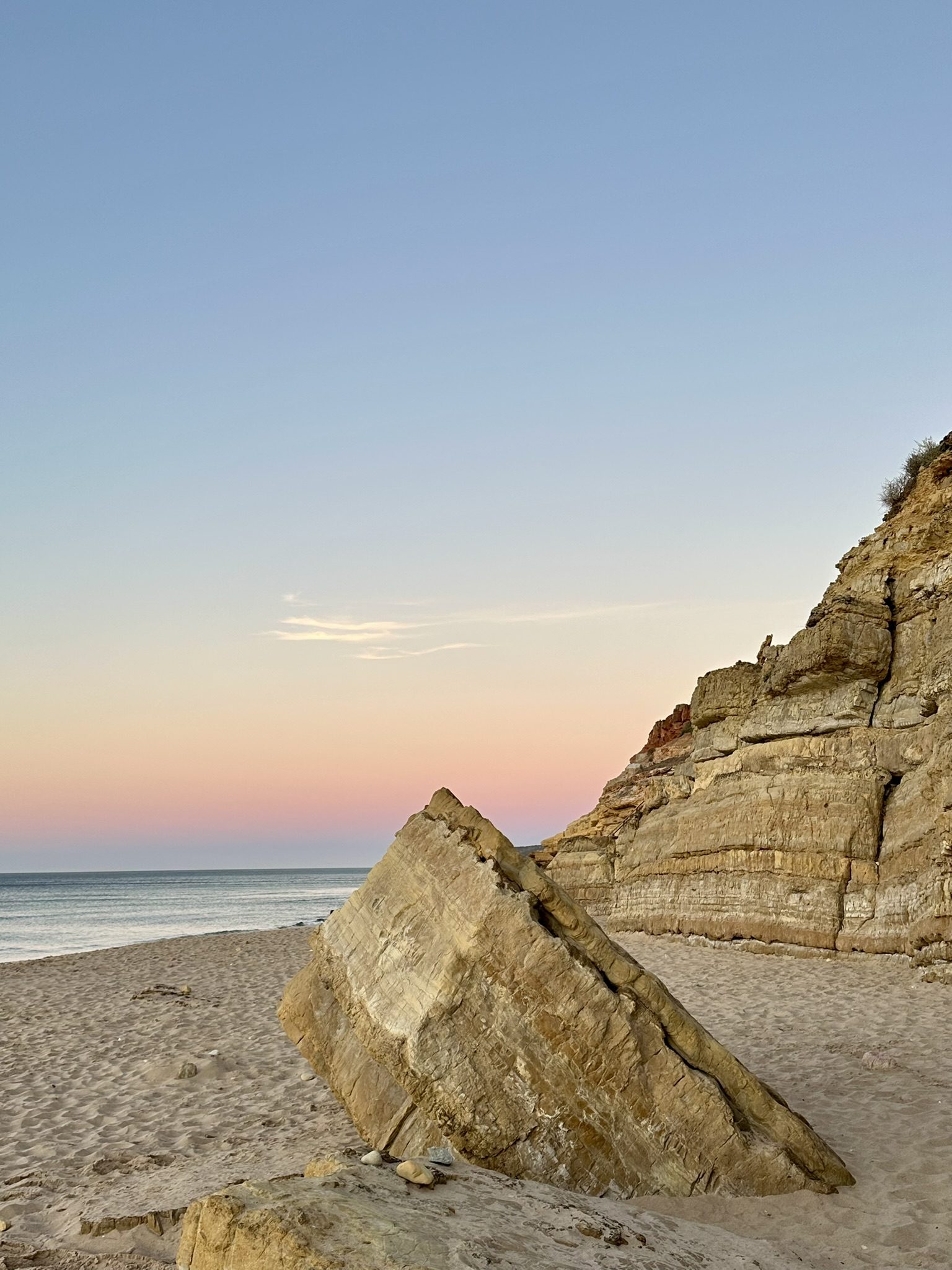 Riesige Felsblöcke am Strand bei Sonnenuntergang mit rosa-blauem Himmel