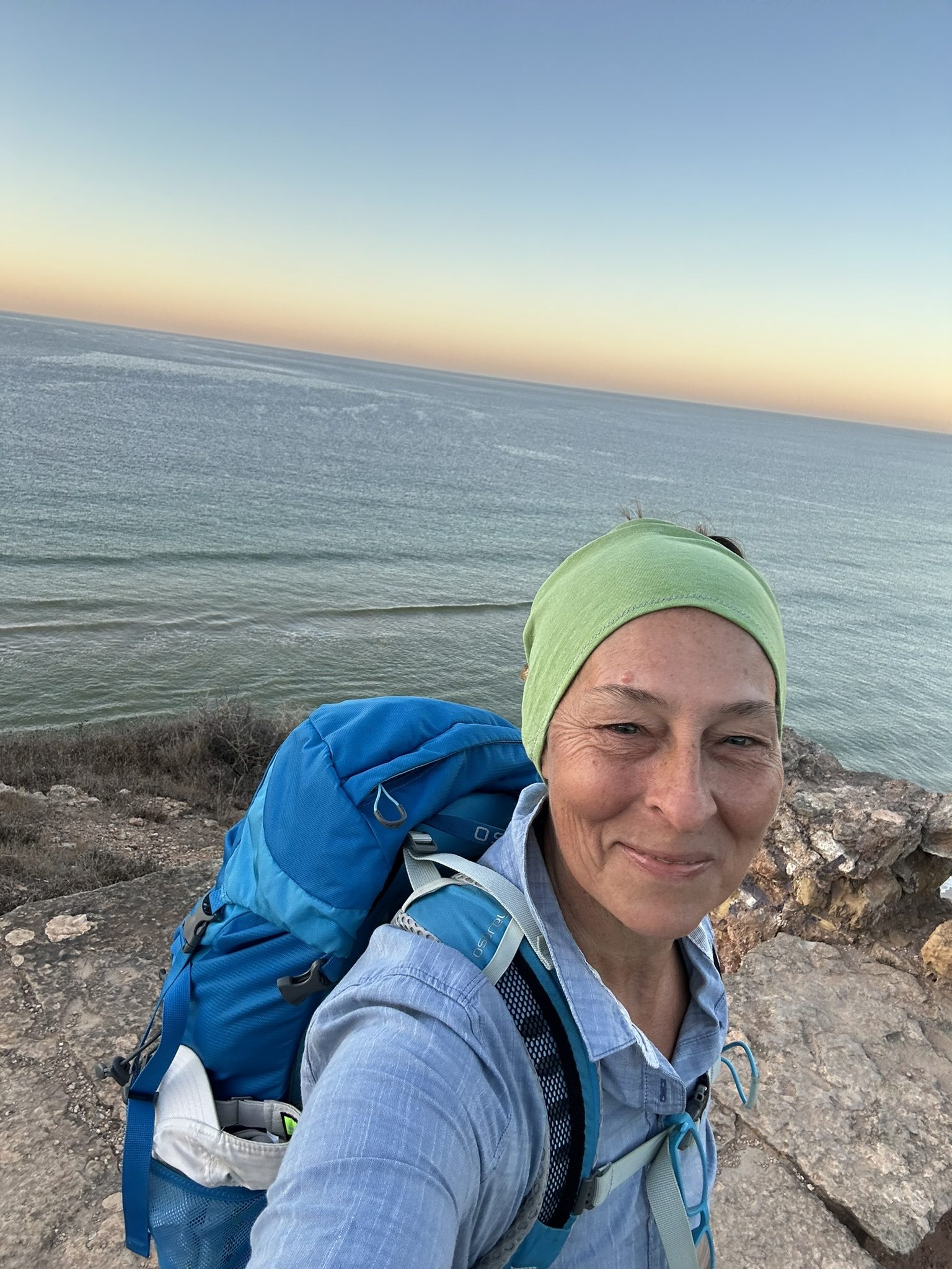 Monika Tatrai lächelt in die Kamera, im Hintergrund Meer und Abendhimmel